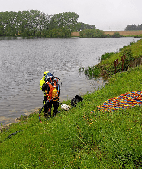 Deux plongeurs se tiennent au bord d'un lac avant l'intervention subaquatique